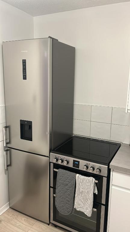 a stainless steel refrigerator in a kitchen with a stove at Cosy Three Bed, Lewisham in London