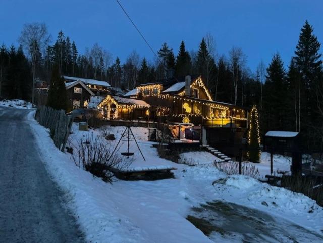 una casa grande con luces de Navidad en la nieve en Koselig enmannsom i tømmerhus, inkl morgenkaffe en Eidsvoll