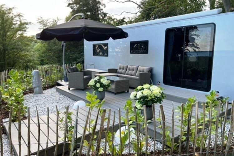 a rv with a couch and an umbrella at Dreamer luxury caravan on the backwaters, Lütow in Lütow