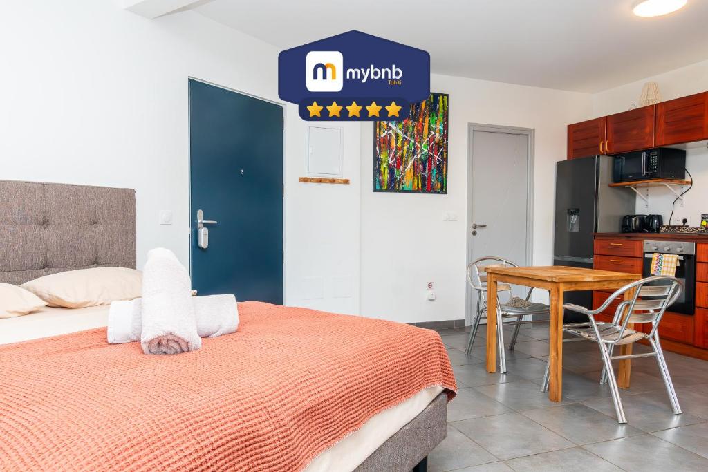 Cet appartement comprend une chambre avec un lit et une table ainsi qu'une cuisine. dans l'établissement Heireva Cosy & Modern Studio Perfect for Explorers and Business Travelers, à Papeete
