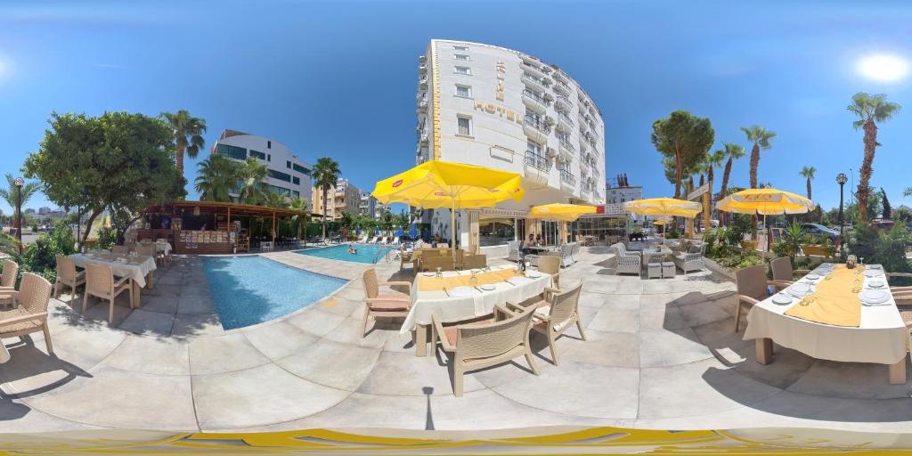 a resort with a pool and tables and yellow umbrellas at Far Life Hotel in Antalya