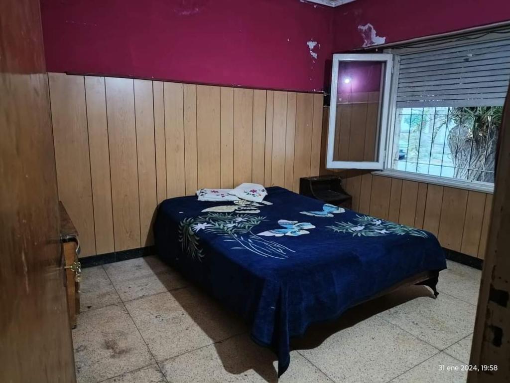 a bedroom with a bed with a blue blanket at La Comuna in Mar del Plata