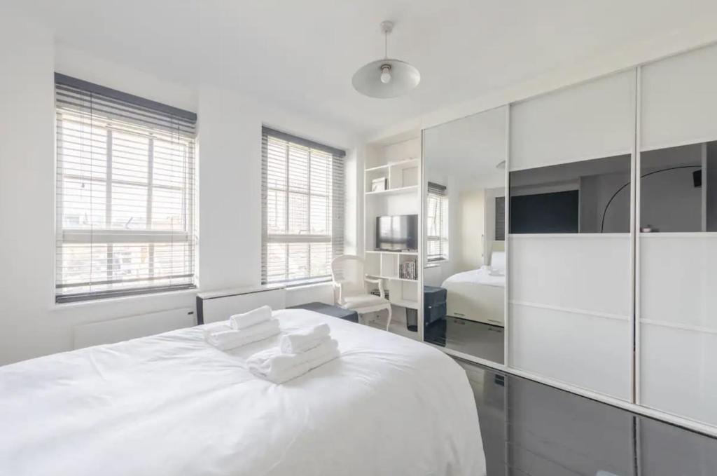 a white bedroom with a large white bed with two towels at Cosy Studio in Bethnal Green in London