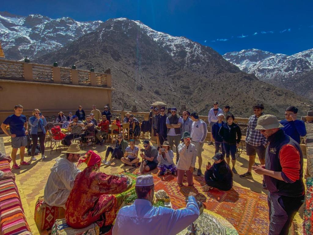 un grupo de personas en una terraza con montañas en el fondo en Kasbah Du Roches Armed en Imlil