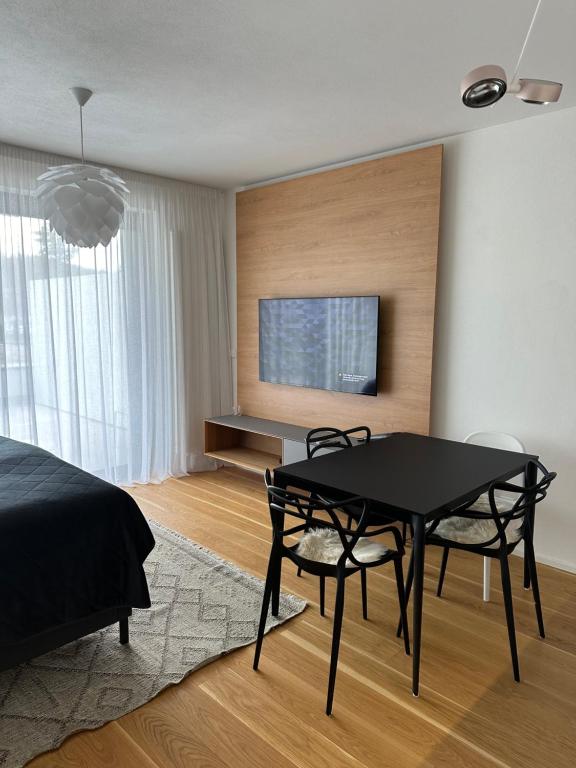 1 dormitorio con mesa negra, sillas y TV en Designový apartmán Molo Lipno, en Český Krumlov