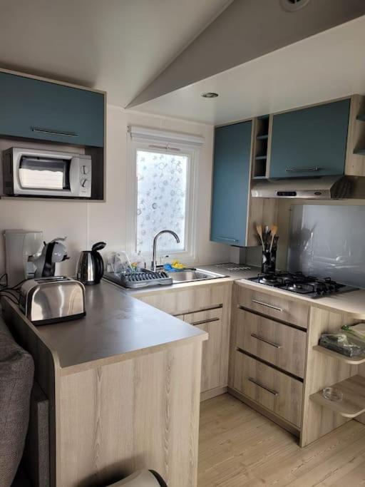 une cuisine avec des armoires bleues et un évier dans l'établissement Mobil-home VI 52 à Vias - La Carabasse - Camping Siblu avec piscine, à Vias