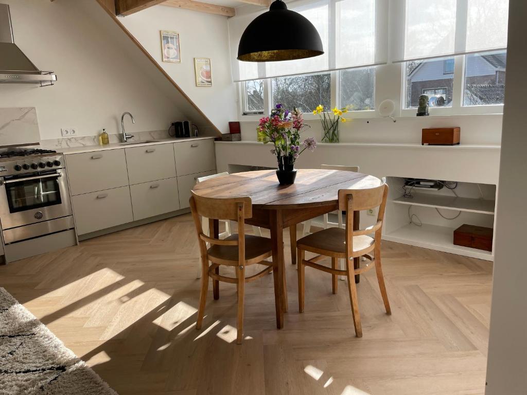 a kitchen with a wooden table and chairs with flowers on it at Villavento in Hoofddorp