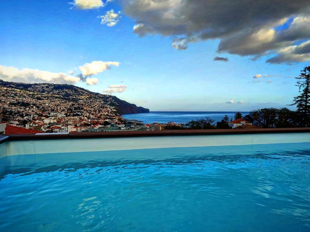 a swimming pool with a view of a city and the ocean at Apartments Madeira Funchal City in Funchal