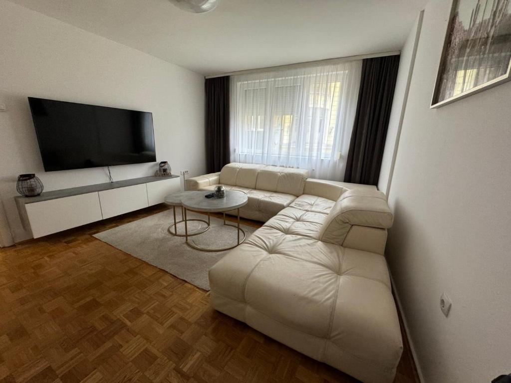 sala de estar con sofá blanco y TV de pantalla plana en Estrada Apartment, en Sarajevo