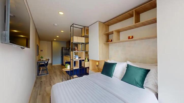 sypialnia z dużym białym łóżkiem z zielonymi poduszkami w obiekcie Apartasuites Cabrera 85 w mieście Bogota