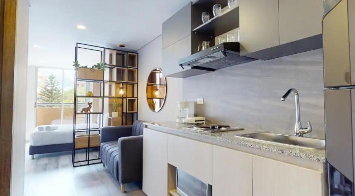 a kitchen with a sink and a living room at Apartasuites Cabrera 85 in Bogotá