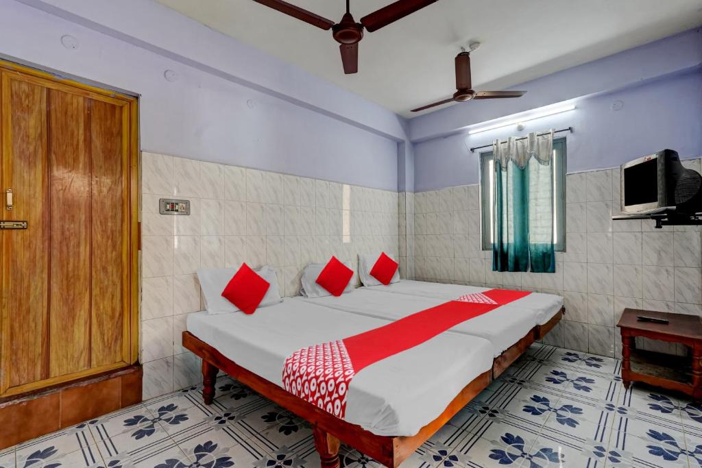 a bedroom with a large bed with red pillows at OYO Flagship Sai Ganesh Deluxe Lodge in Tirupati