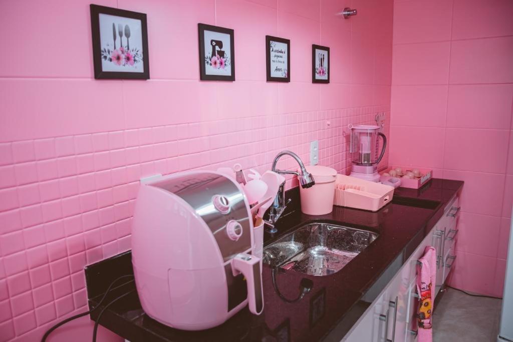 een roze badkamer met een wastafel en een haardroger bij Apartamento rosa in Guarapari
