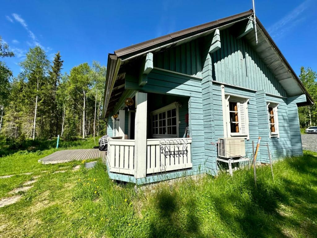 a blue house with a porch on a grass field at Villa kitkanhelmi in Kuusamo