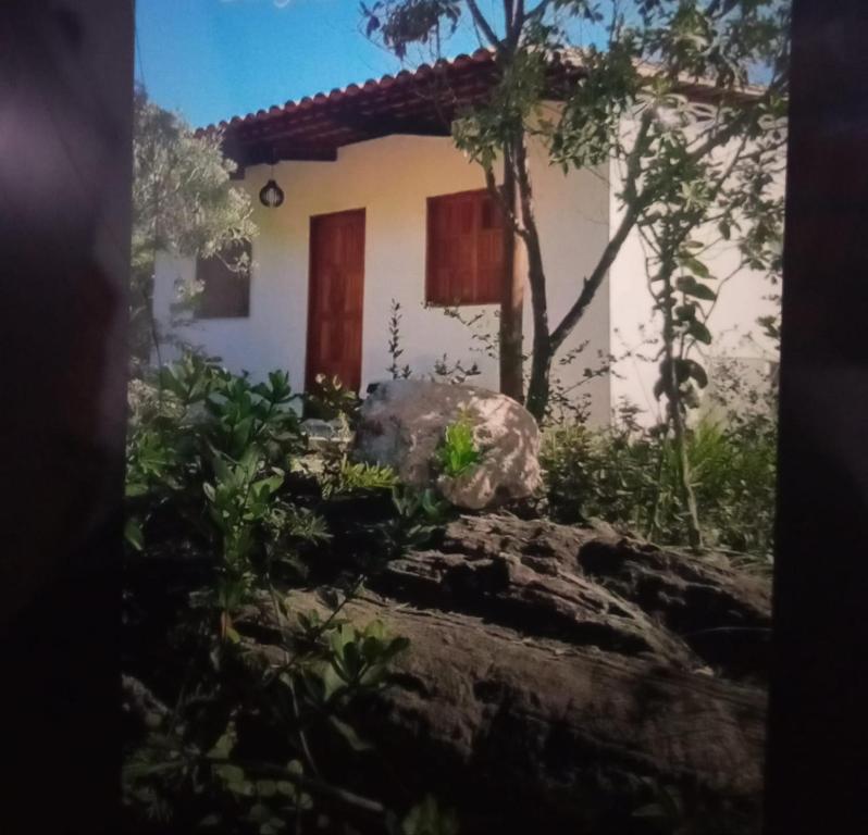 una pequeña casa blanca con una puerta roja en Chalé Mirante do Vale en Piatã