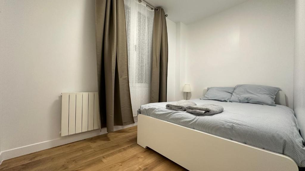 une chambre blanche avec un lit et une fenêtre dans l'établissement Lacharriere-Logement entier 38m2, à Paris