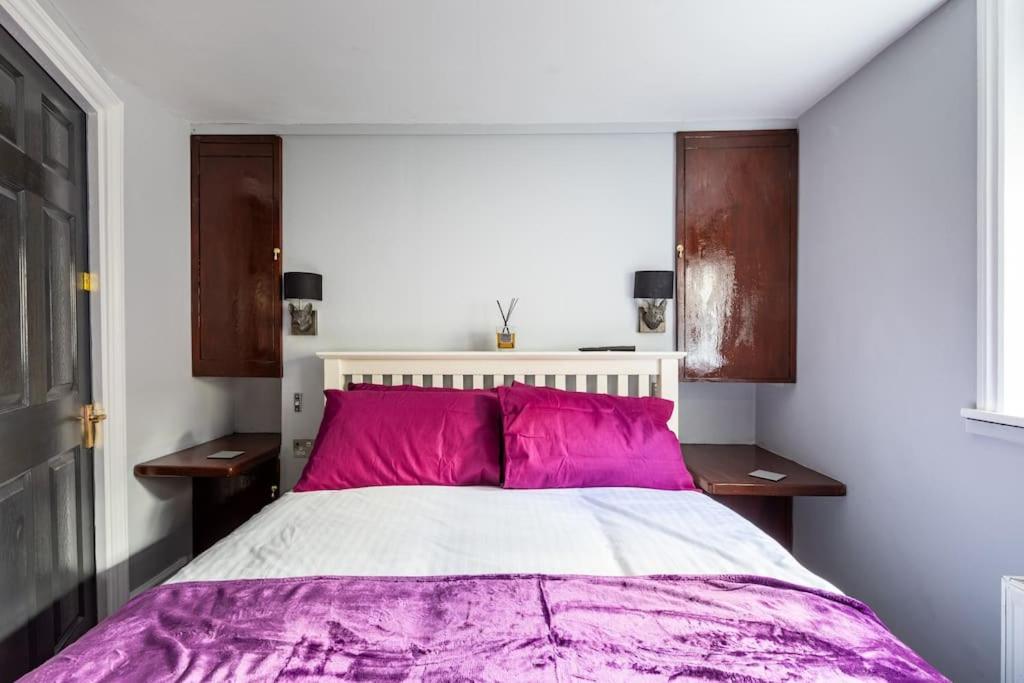 Basement Flat, Regency Square في برايتون أند هوف: غرفة نوم مع سرير كبير مع وسائد وردية