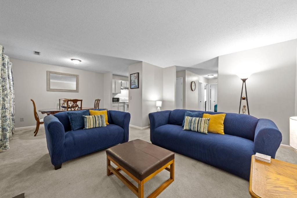 a living room with two blue couches and a table at Comfortable Greensboro Condo in Greensboro