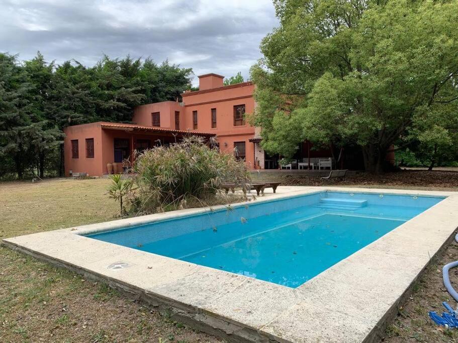 una piscina azul frente a una casa en Casa con piscina y gran parque en Los Cardales en Los Cardales