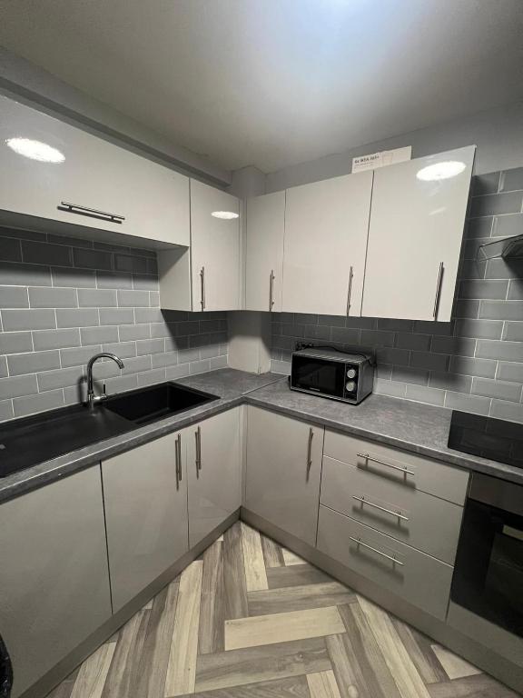 a kitchen with white cabinets and a sink and a microwave at Luxury in luxury out in Nottingham