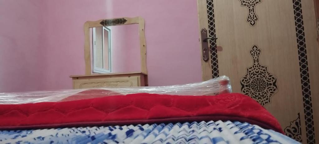 Dormitorio con cama con espejo y manta roja y azul en Ketama Hermanos hutile, en Tlata Ketama