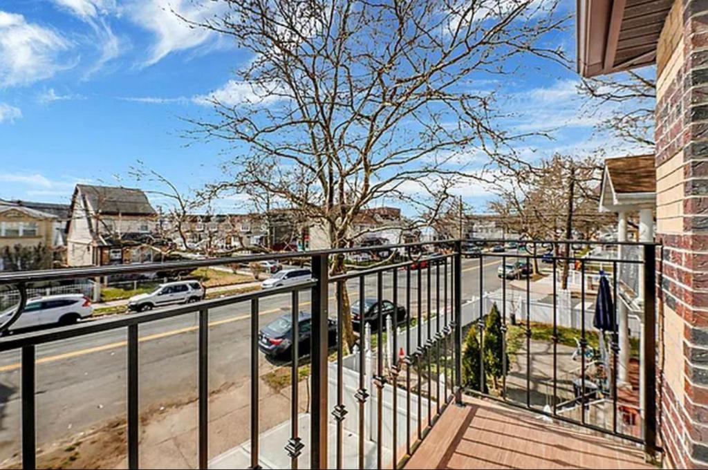 un balcon avec une clôture et une rue avec des voitures dans l'établissement jfk 5 min away, à Cedar Manor