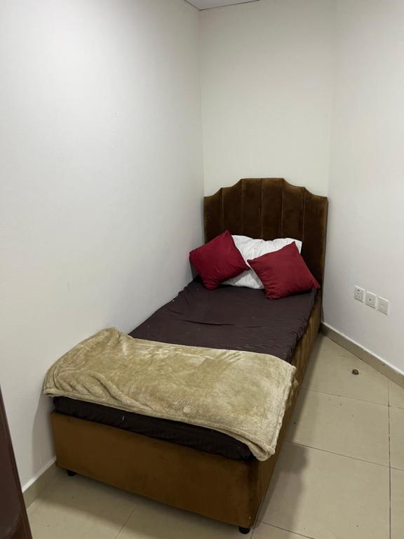 Una cama pequeña con dos almohadas rojas. en F30,R4,Single Room on the beach attach bath en Ajman 