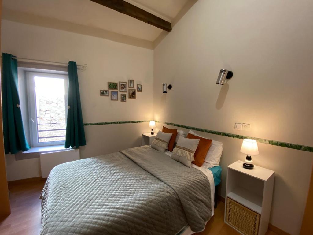 Saint-Geniès-de-Fontedit的住宿－maison de village atypique，一间卧室配有一张床、两盏灯和一个窗户。
