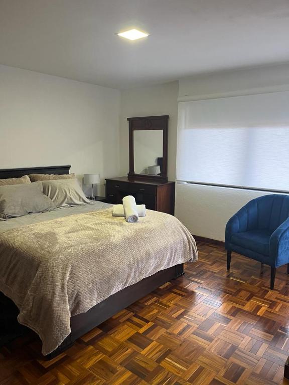 a bedroom with a bed and a blue chair at DEPARTAMENTO DUPLEX 3 Habitaciones EN CUENCA ECUADOR in Cuenca
