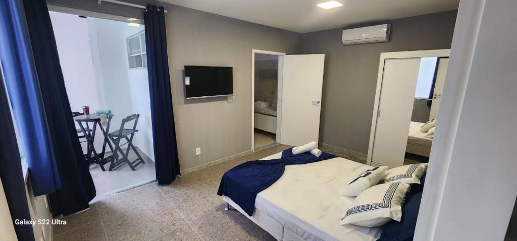 a bedroom with a bed and a television and a table at Atena Flats in Aracaju