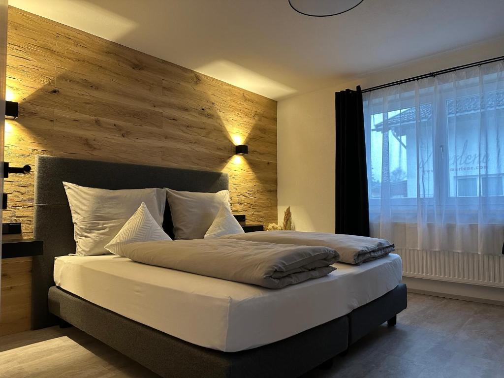 ein Schlafzimmer mit einem großen Bett und einer Holzwand in der Unterkunft Apart7 in Lermoos