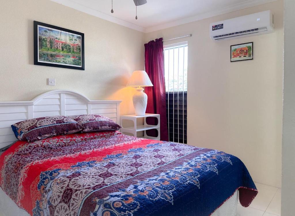 a bedroom with a bed and a lamp and a window at Apartment 6, Kenridge Residences, West coast in Saint James