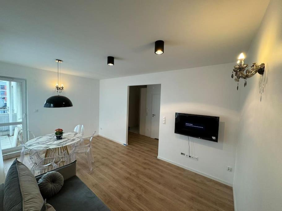 a living room with a table and a tv on the wall at Glamour Apartment in Ochota in Warsaw