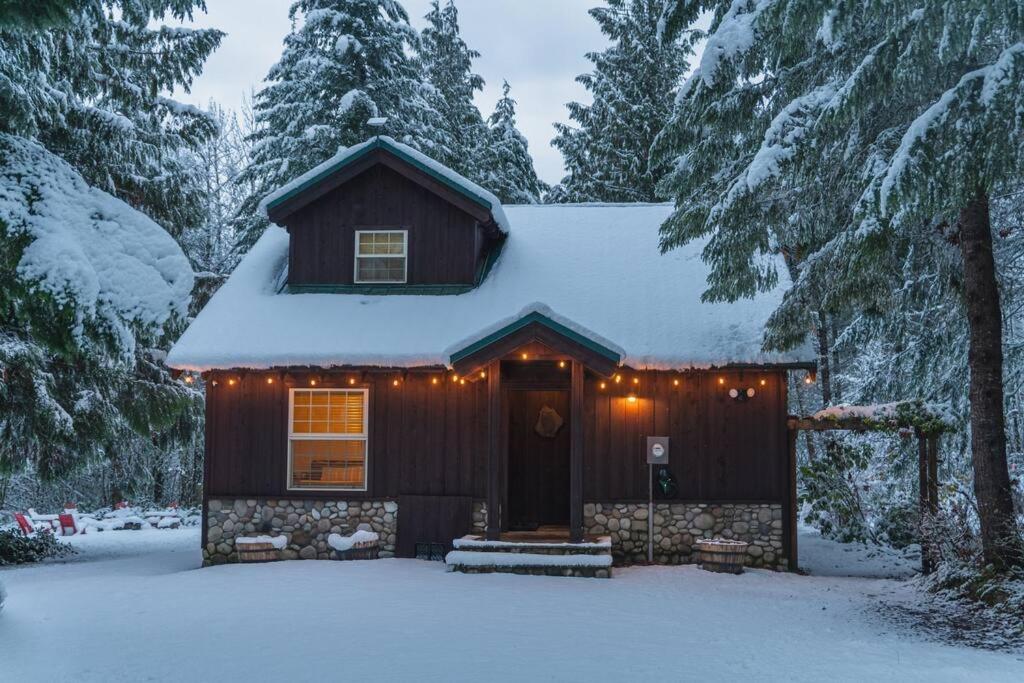a house covered in snow with lights on it at River Rock Chalet :: Hot Tub, Pets, Stevens Pass in Skykomish