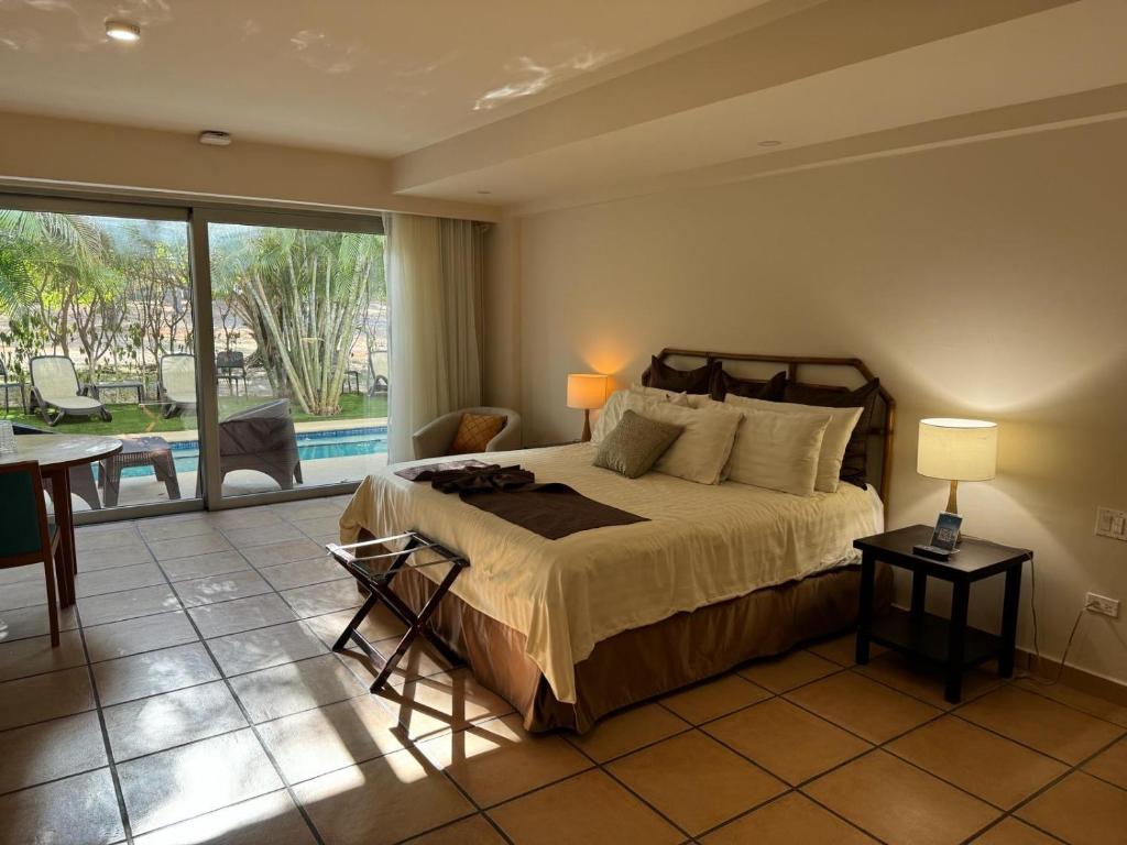 1 dormitorio con cama, mesa y balcón en GOLF CORONADO LUXURY MANGO SUITE PRIVATE POOL FEE INCLUDED en Playa Coronado