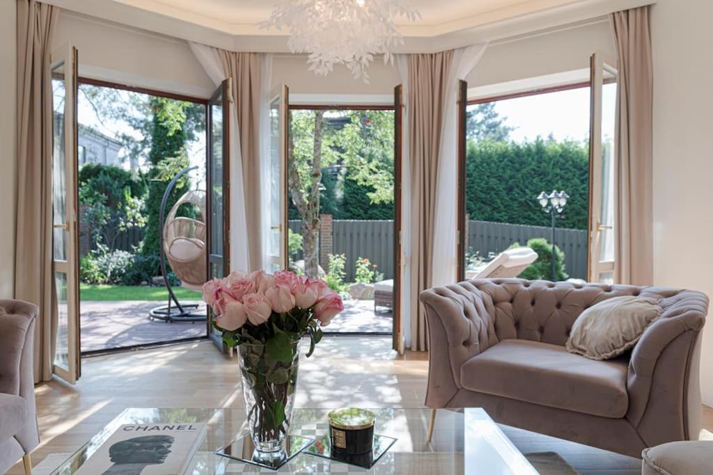 salon z kanapą i wazą różowych róż w obiekcie 252 m² luxury 4 bedroom house in the pine-forest w Wilnie