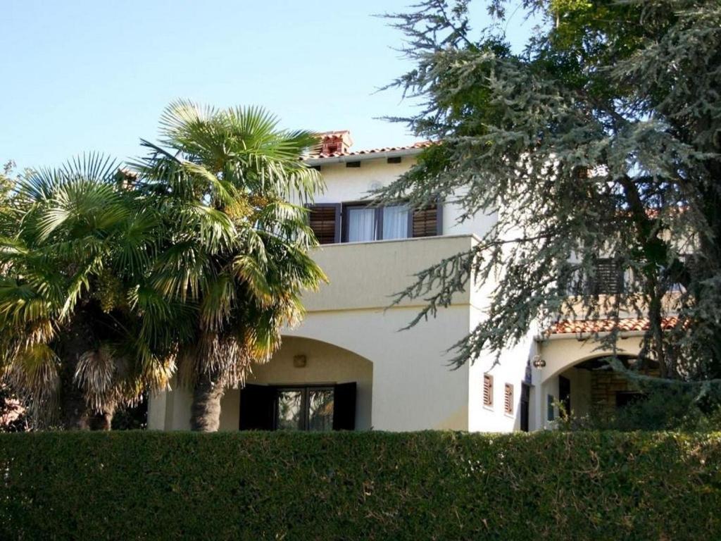 een wit huis met palmbomen ervoor bij Apartments with a parking space Rovinj - 22527 in Rovinj