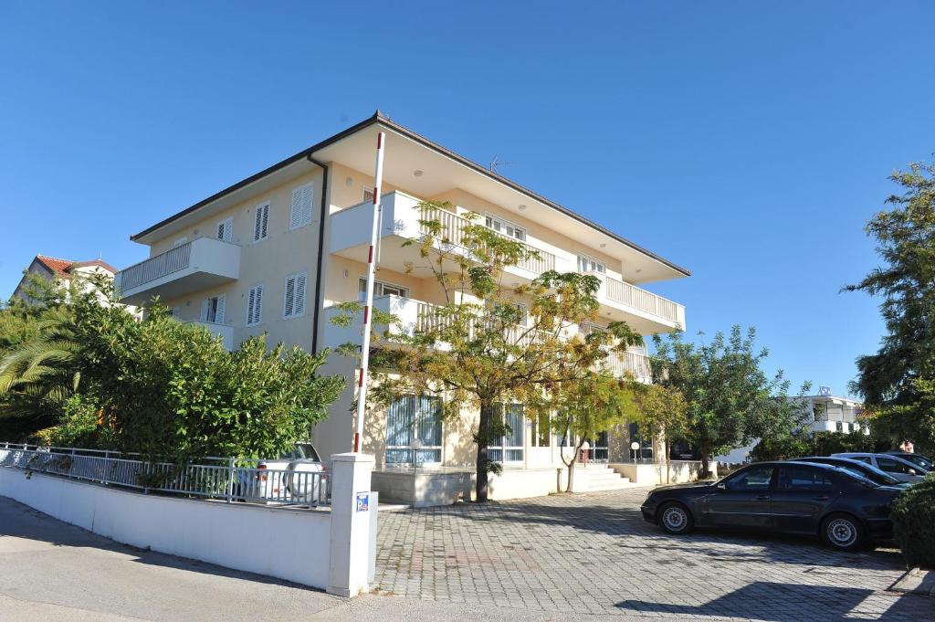 un bâtiment avec une voiture garée devant lui dans l'établissement Apartments and rooms with parking space Trogir - 22531, à Trogir