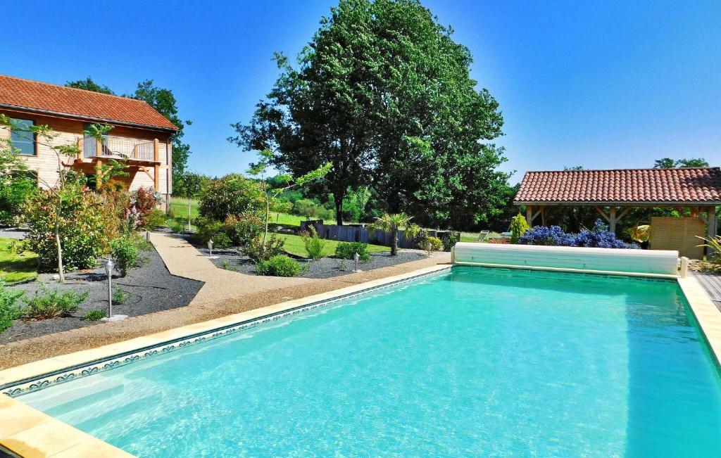 uma piscina num quintal com uma casa em Le Hangar em Castelnaud La Chapelle