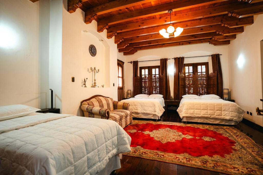 a bedroom with three beds and a red rug at Indian Palace Hotel Boutique Spa & Restaurante in Antigua Guatemala