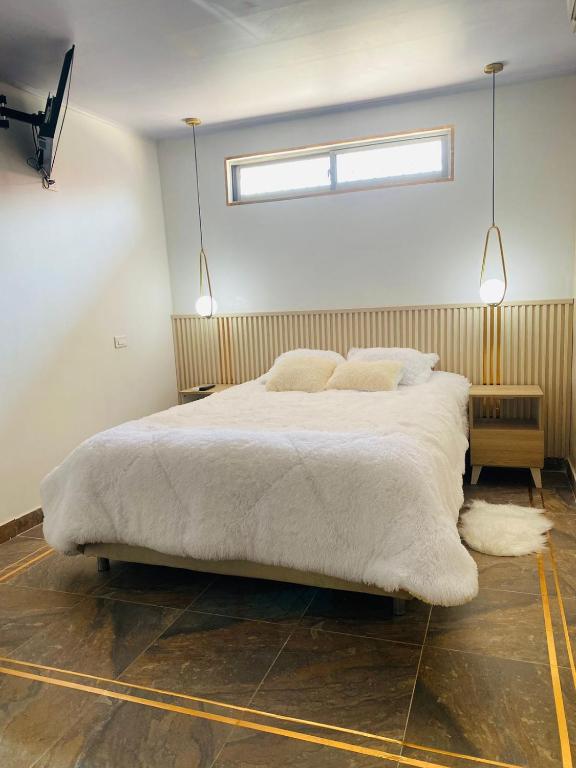 um quarto com uma grande cama branca e 2 almofadas em Apartaestudio Turbaco em Turbaco