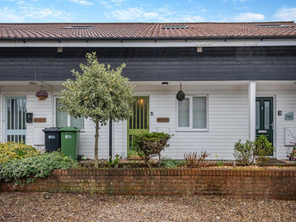 a white house with a brick fence in front of it at Wanderer in Sutton