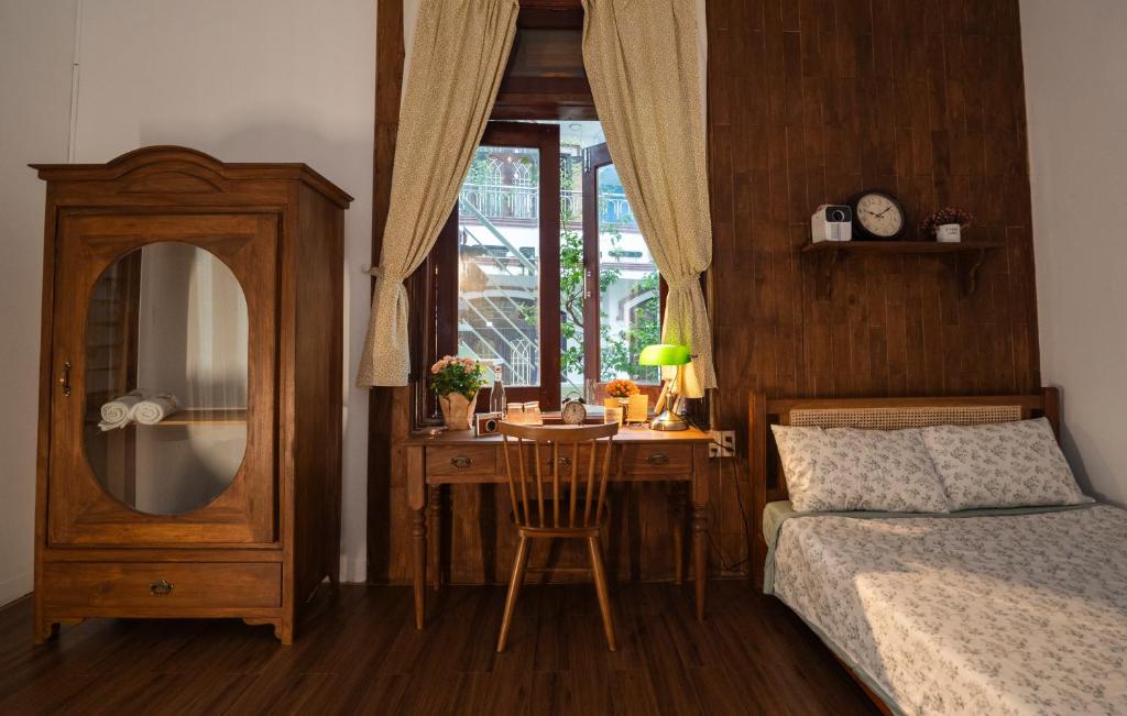 Schlafzimmer mit einem Bett und einem Schreibtisch mit einem Spiegel in der Unterkunft Hue Memories homestay 2 in Hue