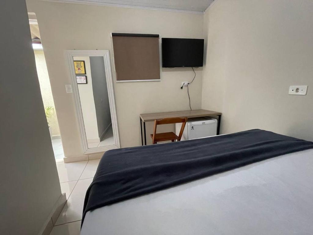 1 dormitorio con cama, mesa y espejo en Hostel Quartos com banheiro individual perto do Aeroporto en Guarulhos