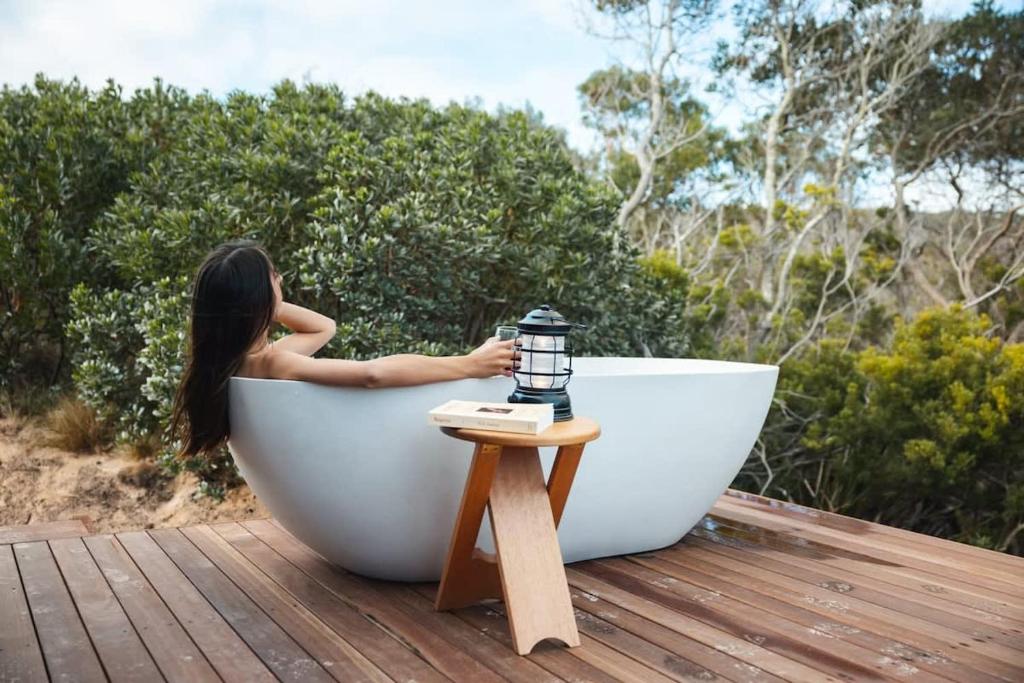 eine Frau, die in einer Badewanne auf einem Deck sitzt in der Unterkunft Tiny Rupetta in Currie