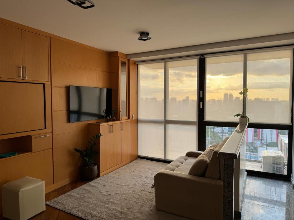 a living room with a couch and a large window at AP1407 - Região dos hospitais, piscina e garagem in São Paulo