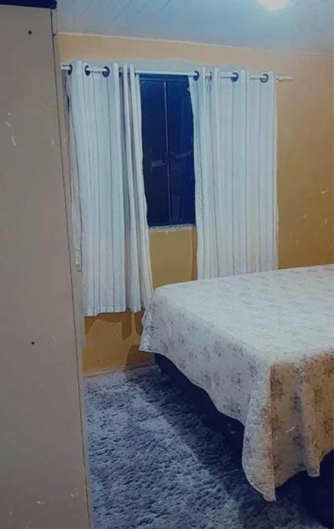 um quarto com uma cama e uma janela com cortinas em Ap mobiliado em Guarapuava