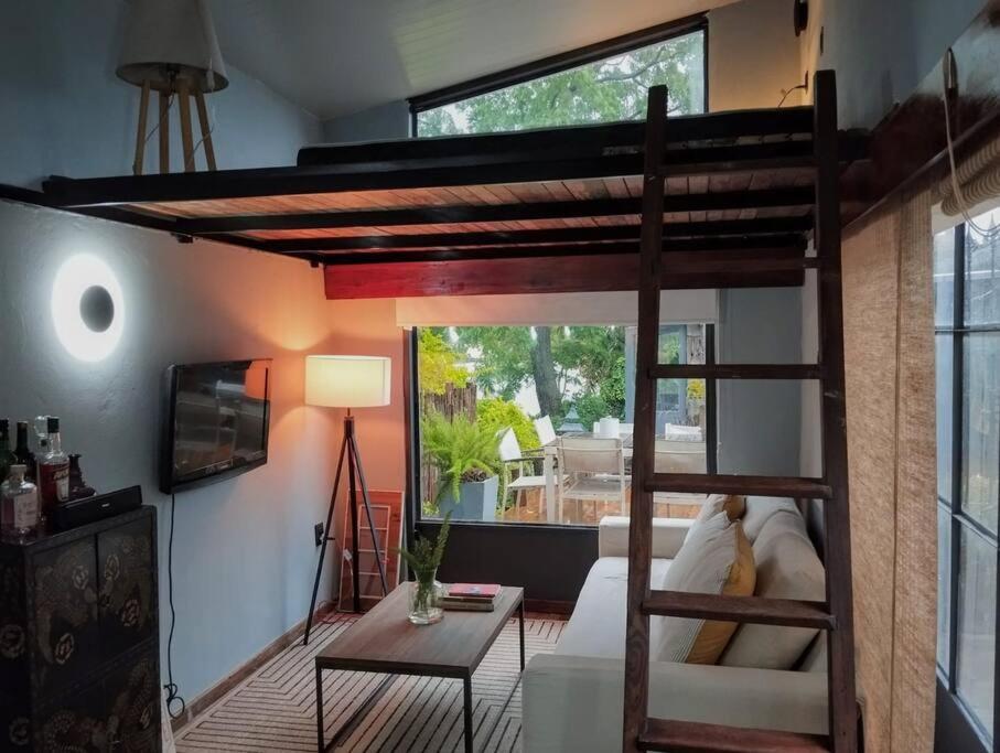 Habitación con cama elevada y sala de estar. en Guest Tiny House - lake side en Montevideo