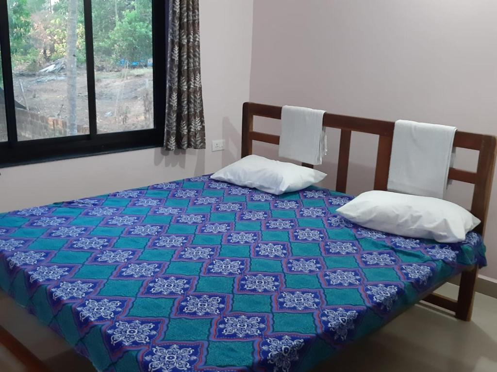 a bed with a blue and green quilt on it at Dias Guest House in Canacona