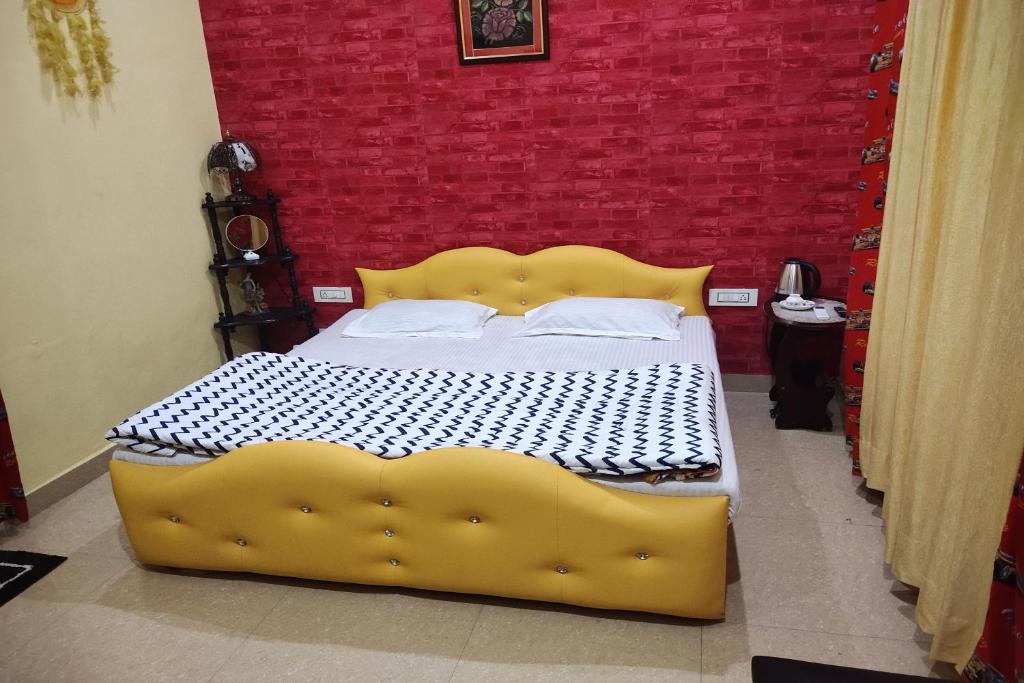 Cama amarilla en habitación con pared roja en OYO Home Abhishek Homestay, en Pathankot